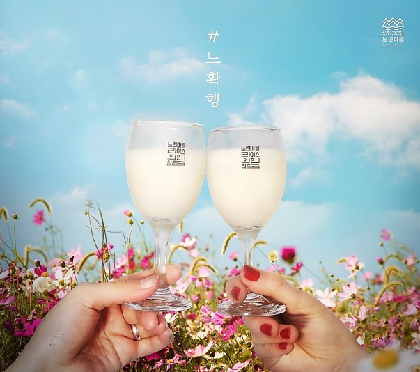 봄을 배경으로 와인잔에 막걸리를 따라서 건배하는 사진