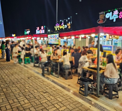 밤의 낭만포차거리 식당에서 야외식사를 하고 있는 사람들