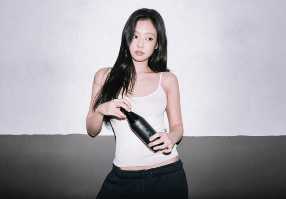 제니가 흰색 셔츠를 입고 스탠리를 들고 있는 모습